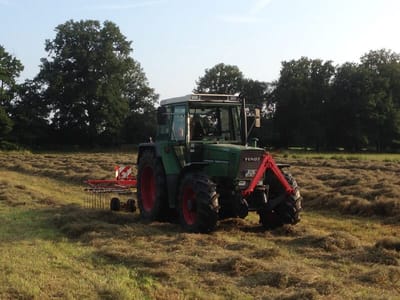 Traktor mit Kreiselheuer wendet das Heu auf der Wiese