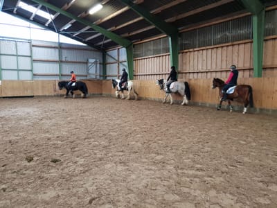 Reitschülerinnen auf Ponys in der Reithalle