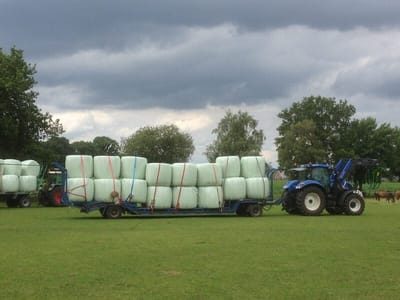 Heulageernte: in Folie gewickelte Ballen auf dem Anhänger eines Traktors