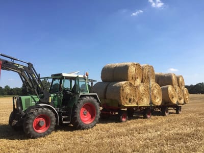 Strohbergung: Traktor mit Anhänger voller Strohballen auf dem Stoppelfeld