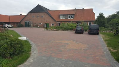 Gepflasterte Hofeinfahrt mit Wohnhaus und Stallgebäuden des Braaklander Hofs